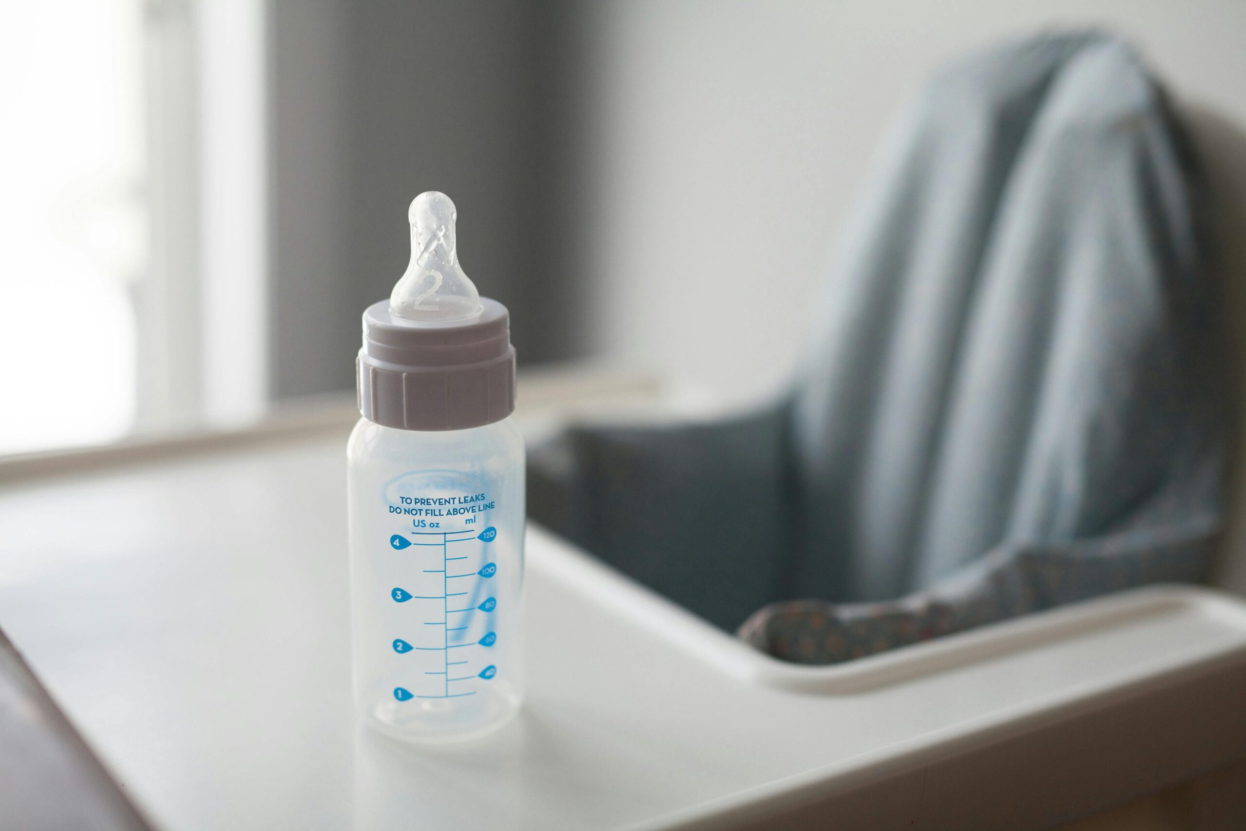 A baby bottle placed on a high chair, captured in natural light, suggesting a nurturing environment.